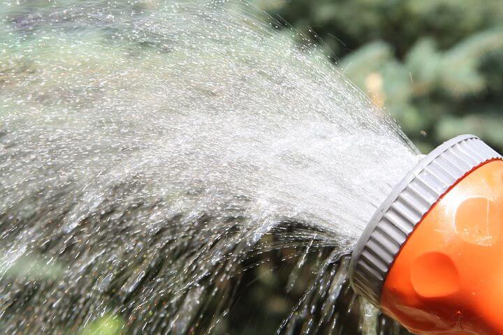 Orange garden hose spraying water